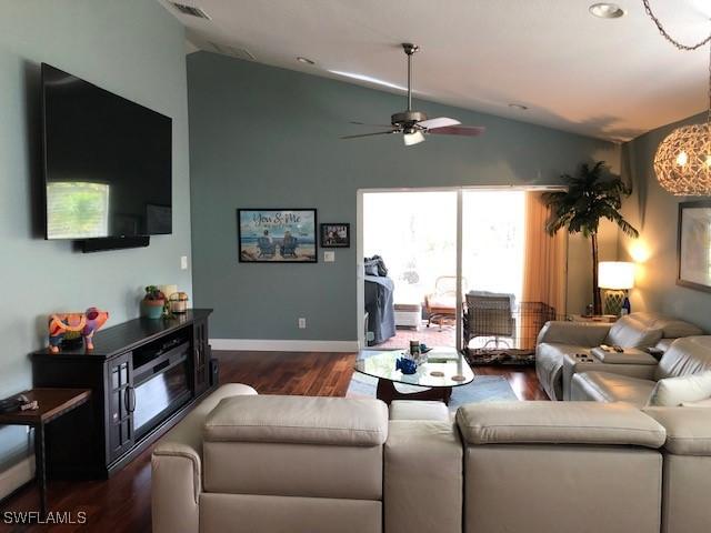 living room featuring lofted ceiling, dark wood-type flooring, and ceiling fan