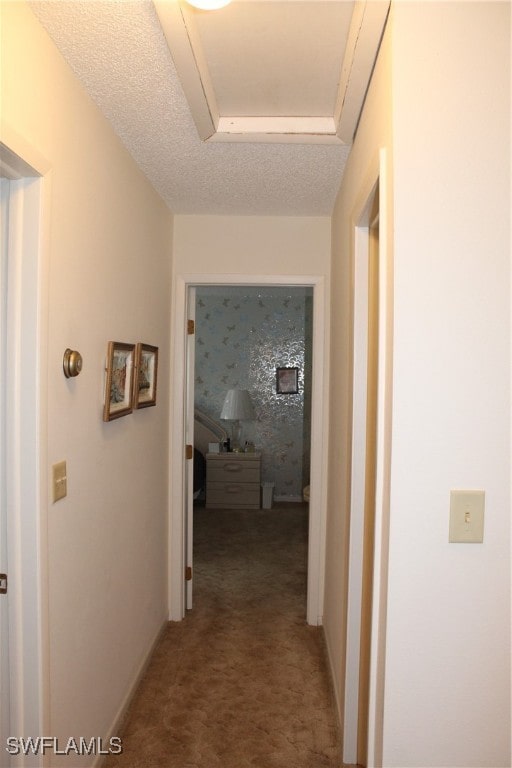 hall featuring a textured ceiling and carpet flooring