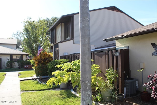 view of home's exterior with a lawn and central AC