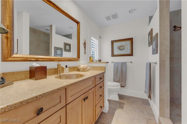 bathroom featuring tile patterned floors, tiled shower, toilet, and vanity