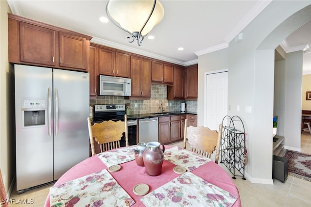 kitchen with ornamental molding, backsplash, light tile patterned floors, stainless steel appliances, and sink