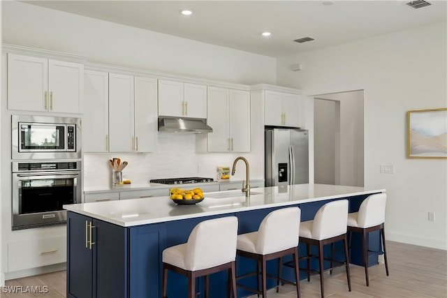 kitchen with a kitchen island with sink, light hardwood / wood-style flooring, stainless steel appliances, and a kitchen breakfast bar