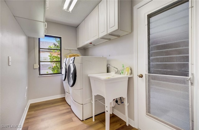 washroom featuring cabinets, light wood-type flooring, and washing machine and clothes dryer