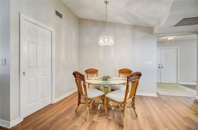 dining area with light wood-type flooring and an inviting chandelier