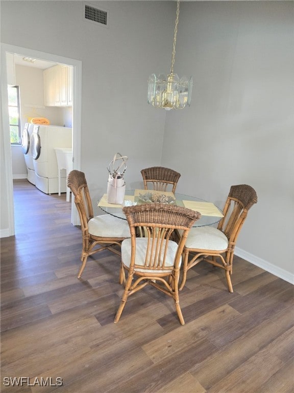 dining area with a notable chandelier, dark wood-type flooring, and washer and dryer