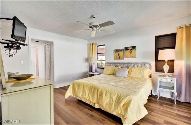 bedroom with a textured ceiling, ceiling fan, and hardwood / wood-style flooring