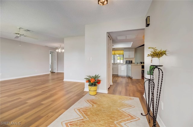 interior space featuring light wood-type flooring, a textured ceiling, and an inviting chandelier