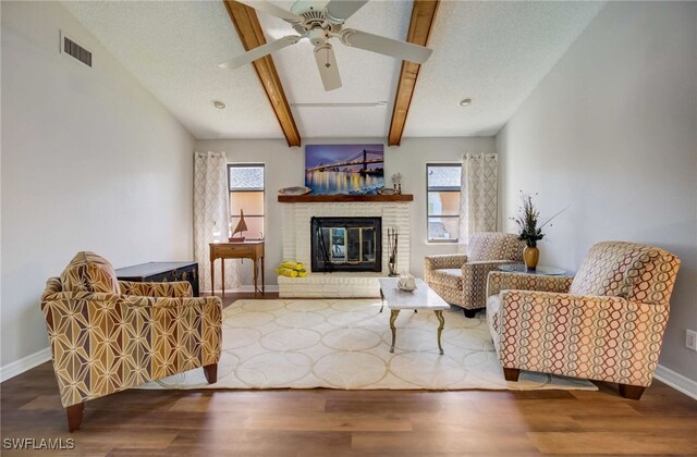 living room featuring ceiling fan, a brick fireplace, hardwood / wood-style floors, and a healthy amount of sunlight