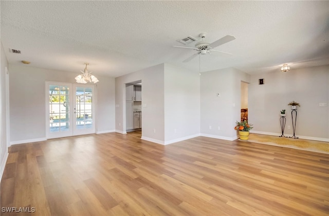 spare room featuring a textured ceiling, ceiling fan with notable chandelier, and light hardwood / wood-style flooring