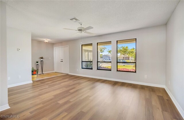 unfurnished living room with ceiling fan, a textured ceiling, and light hardwood / wood-style flooring