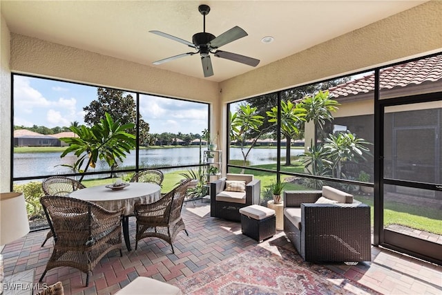 sunroom / solarium with ceiling fan and a water view