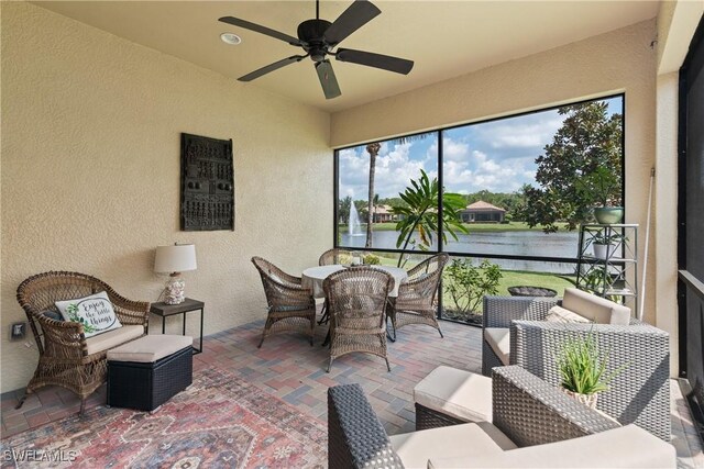 sunroom / solarium with ceiling fan and a water view