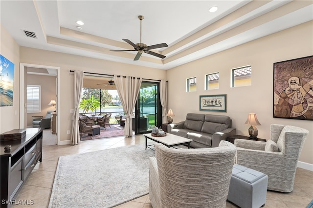 living room with light tile patterned floors and a tray ceiling