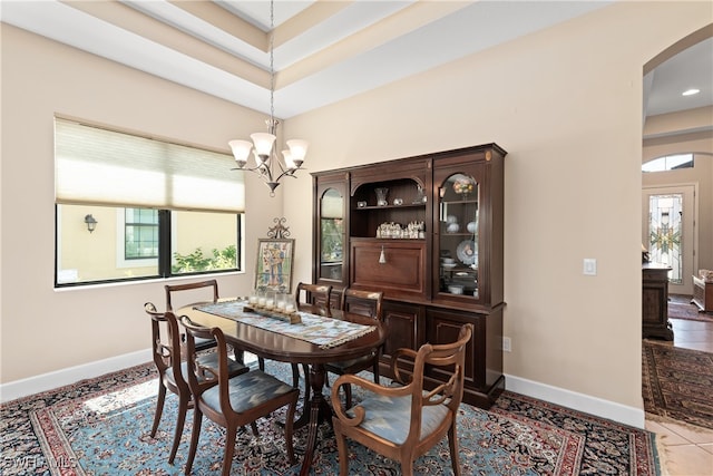 dining area with light tile patterned floors, a notable chandelier, and a towering ceiling