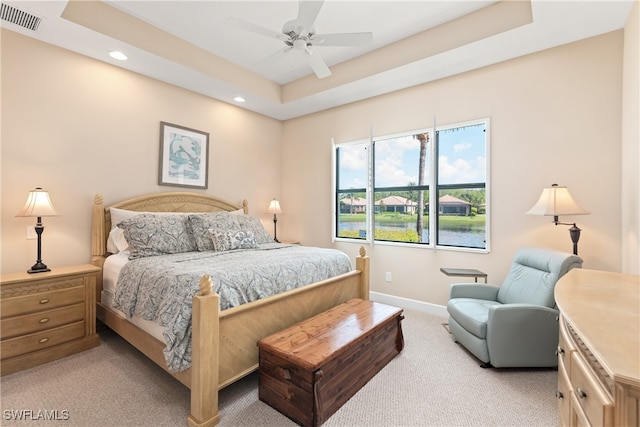 carpeted bedroom featuring ceiling fan and a tray ceiling