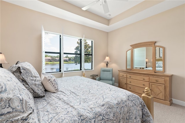 bedroom featuring ceiling fan, light colored carpet, and a water view