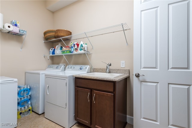 clothes washing area with cabinets, light tile patterned floors, washing machine and clothes dryer, and sink