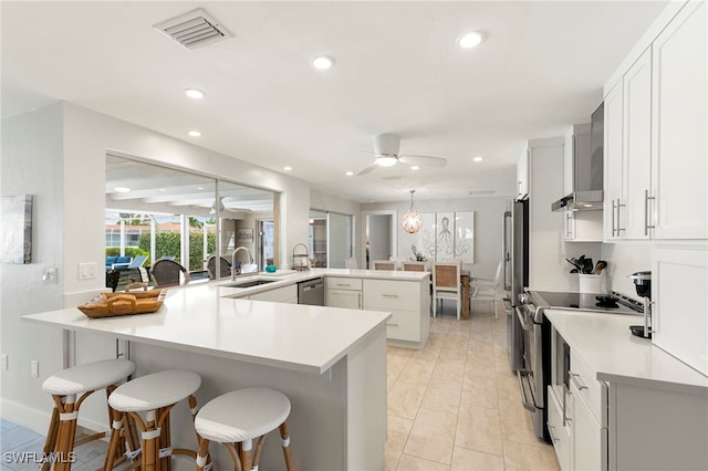 kitchen featuring visible vents, a ceiling fan, a peninsula, stainless steel appliances, and a sink