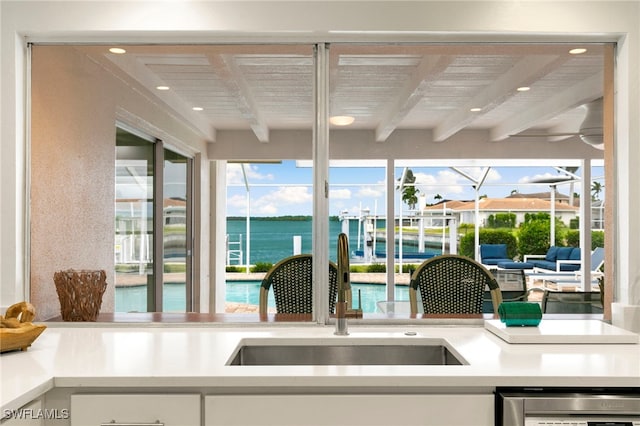 kitchen with recessed lighting, a sink, white cabinets, light countertops, and beam ceiling