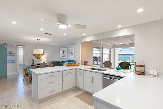 kitchen with a barn door, visible vents, dishwasher, a peninsula, and a sink