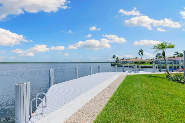 view of dock with a lawn and a water view