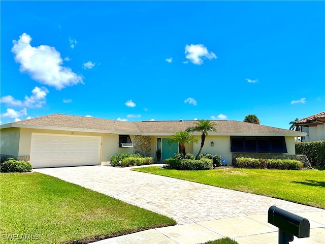 single story home with a garage, a front yard, decorative driveway, and stucco siding