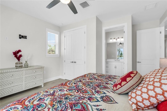 bedroom with wood finished floors, a sink, visible vents, a ceiling fan, and a closet