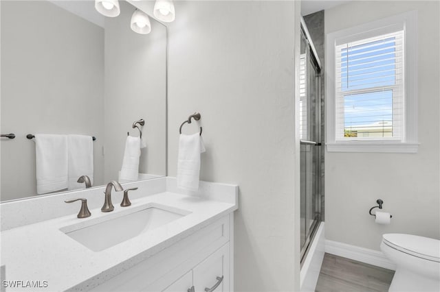 bathroom featuring baseboards, toilet, wood finished floors, vanity, and a shower stall