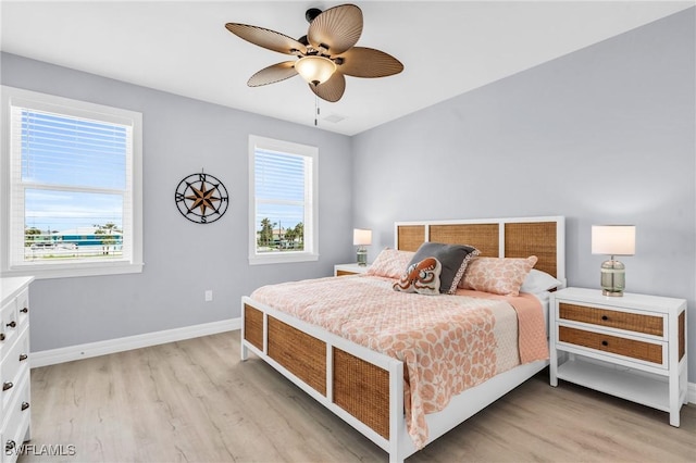 bedroom with ceiling fan, light wood finished floors, and baseboards