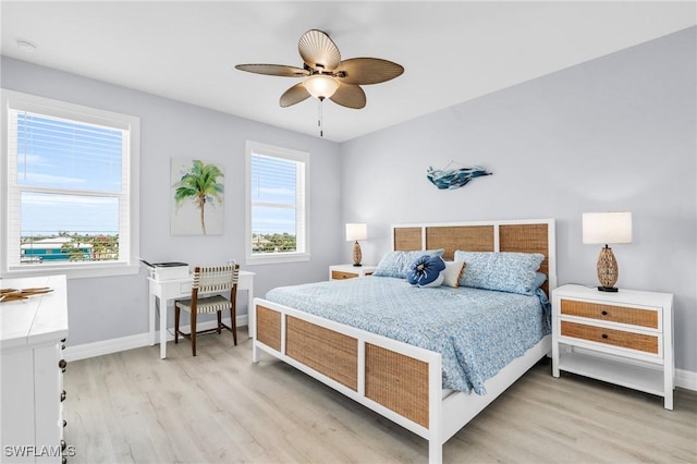 bedroom with light wood finished floors, a ceiling fan, and baseboards