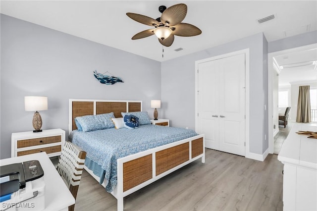 bedroom with ceiling fan, light wood-style flooring, visible vents, baseboards, and a closet