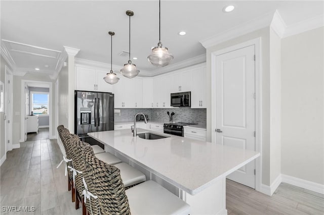 kitchen featuring a center island with sink, light countertops, white cabinets, a sink, and black appliances