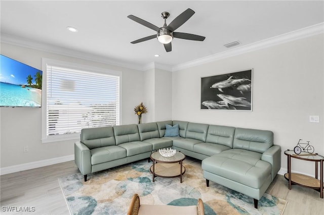 living area featuring ceiling fan, light wood-style flooring, visible vents, baseboards, and ornamental molding