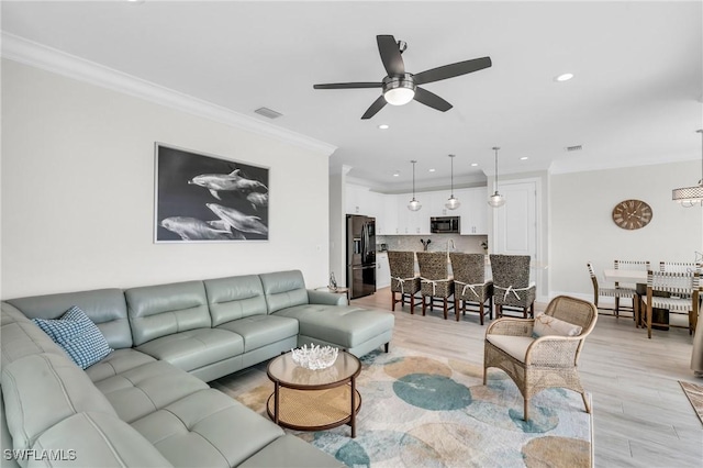 living room with light wood-type flooring, visible vents, crown molding, and recessed lighting