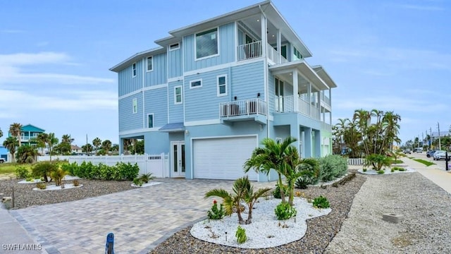 view of front of property featuring a balcony, an attached garage, fence, decorative driveway, and board and batten siding