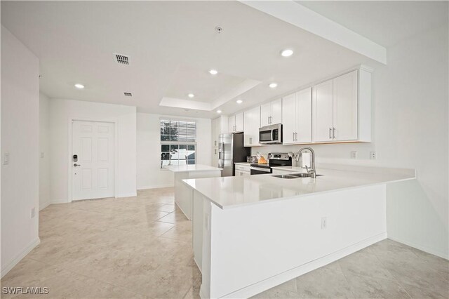 kitchen featuring stainless steel appliances, a raised ceiling, light countertops, visible vents, and a sink