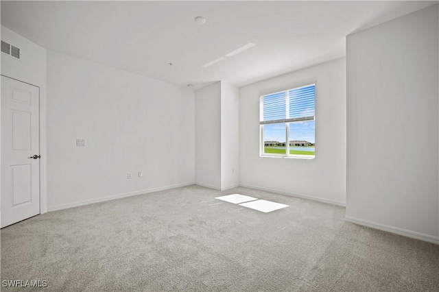 carpeted spare room featuring baseboards and visible vents