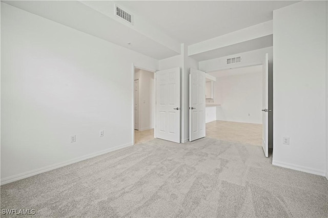 carpeted spare room with visible vents and baseboards