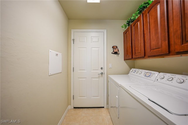 clothes washing area with cabinets, washing machine and clothes dryer, and light tile patterned floors