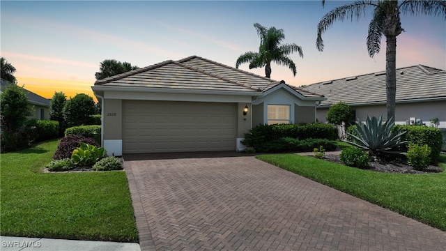 single story home with a garage and a lawn