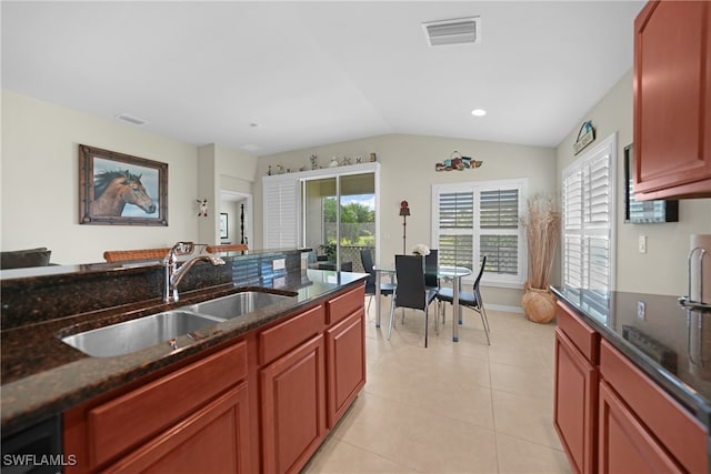 kitchen featuring dark stone countertops, sink, light tile patterned floors, and vaulted ceiling