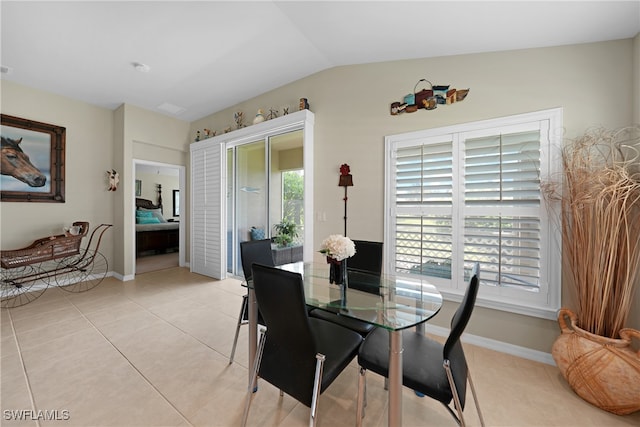 dining room featuring light tile patterned floors, vaulted ceiling, and plenty of natural light