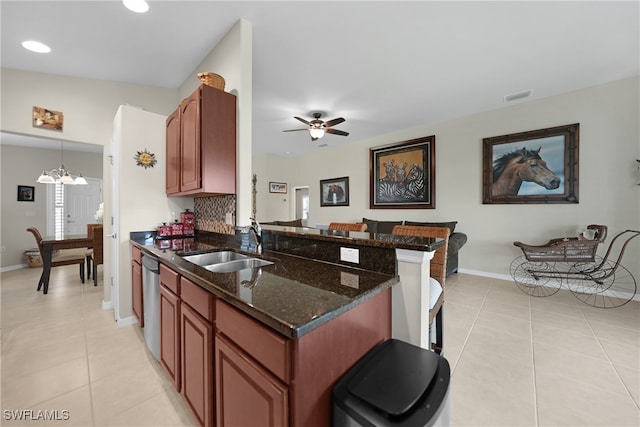 kitchen featuring dark stone counters, sink, hanging light fixtures, and light tile patterned floors