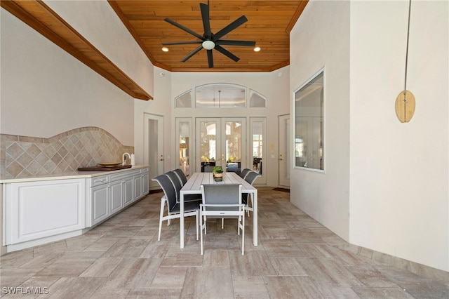 dining room with ceiling fan, french doors, a towering ceiling, and wood ceiling