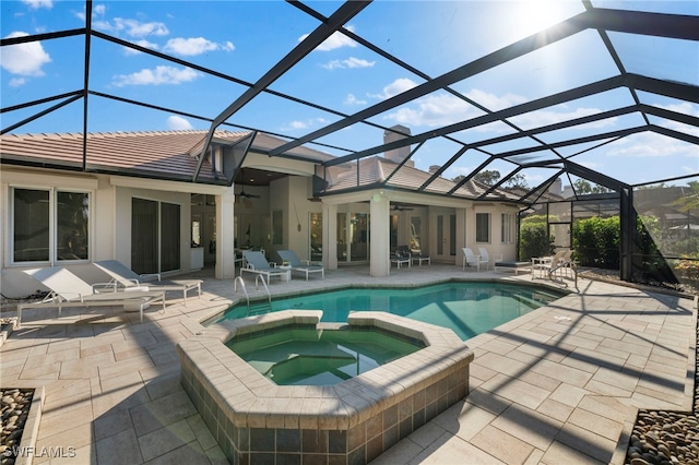 view of pool featuring a patio, ceiling fan, an in ground hot tub, and glass enclosure