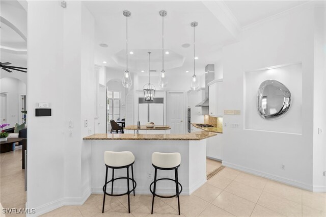 kitchen featuring pendant lighting, light stone countertops, white cabinetry, and kitchen peninsula