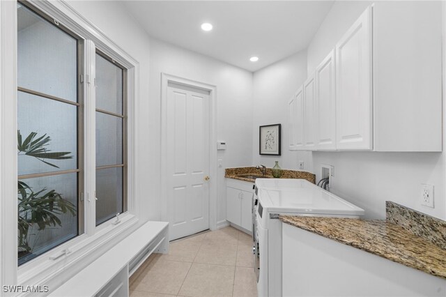 washroom featuring sink, light tile patterned flooring, cabinets, and washer hookup