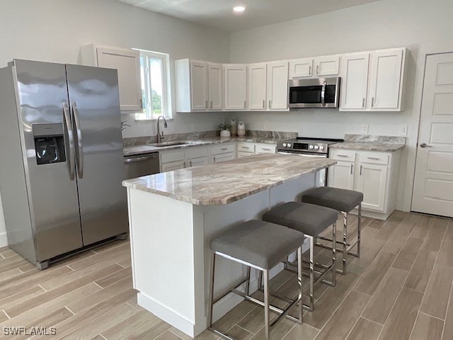 kitchen featuring appliances with stainless steel finishes, sink, a breakfast bar area, and white cabinets