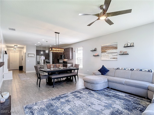 living room featuring hardwood / wood-style flooring, sink, and ceiling fan