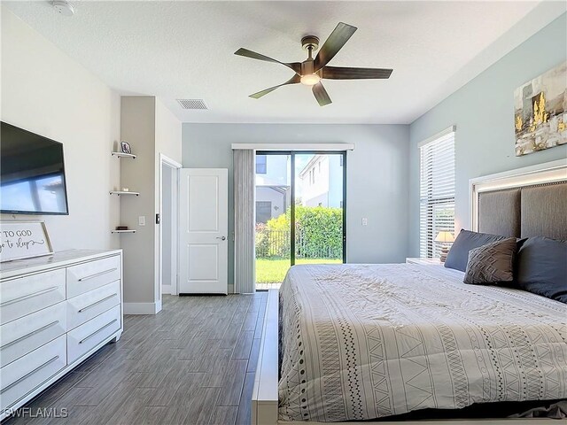 bedroom featuring ceiling fan, dark hardwood / wood-style floors, access to outside, and a textured ceiling